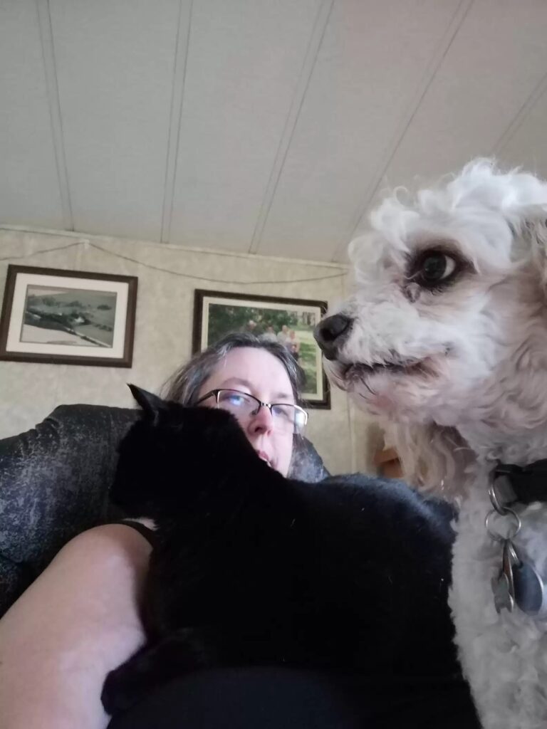 cat and dog sitting on mother's lap